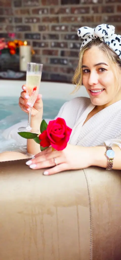 Guest smiling with a glass of sparkling wine and a red rose